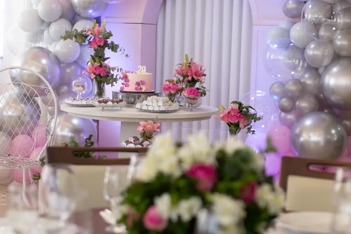 Birthday party table with cake, flowers and balloon decorations